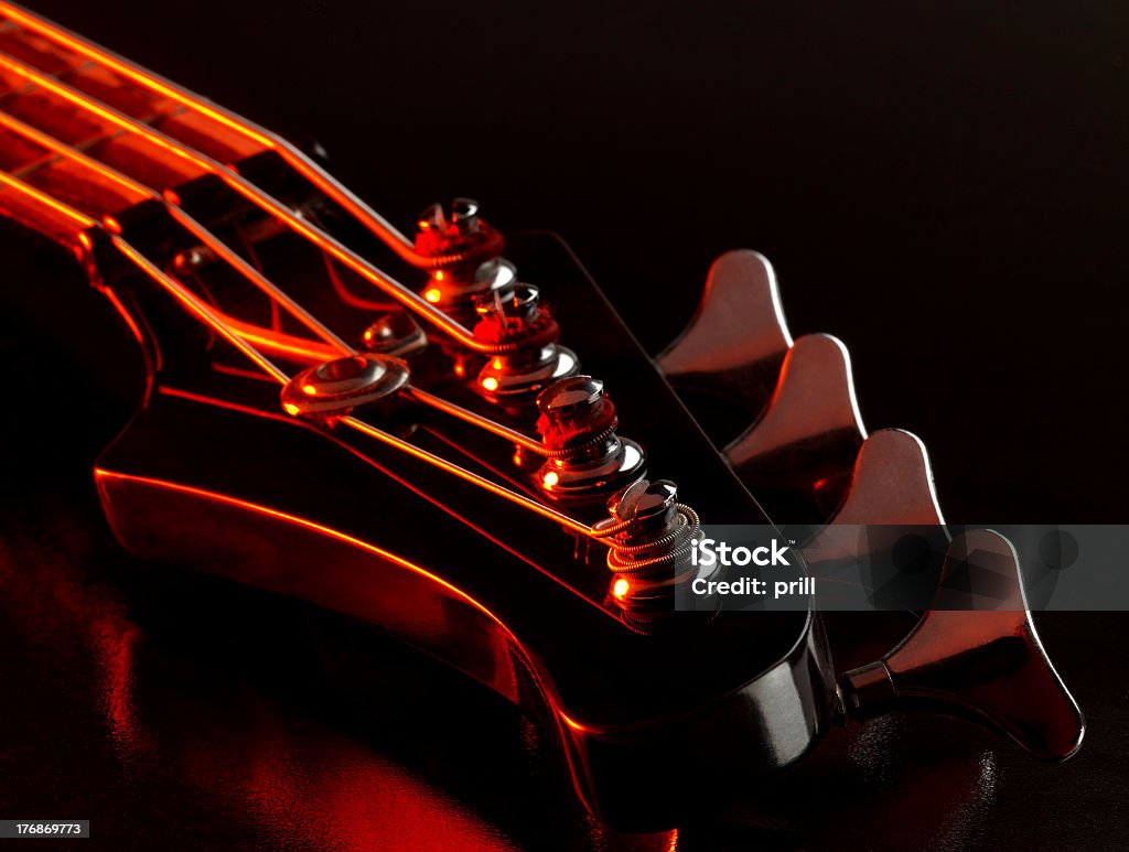 bass guitar detail detail of a bass guitar with red light in dark back Electric Guitar Stock Photo