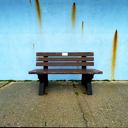 Wooden bench by a stained blue wall in Canvey Island