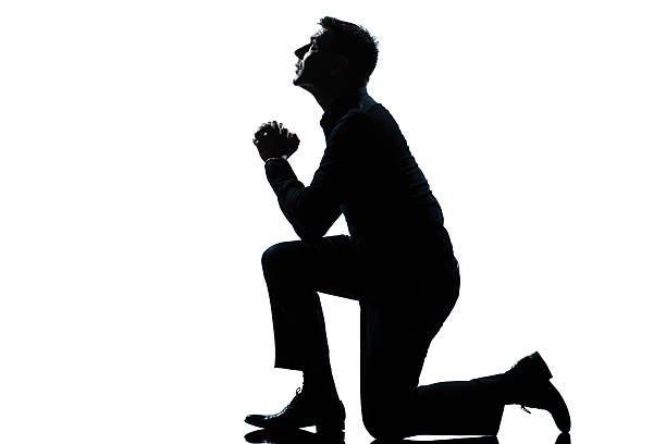 istock silhouette man kneeling praying  full length 176870524