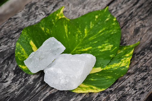 White alum cubes on leaves and wooden plank, alternative medical treatment and body care concept.