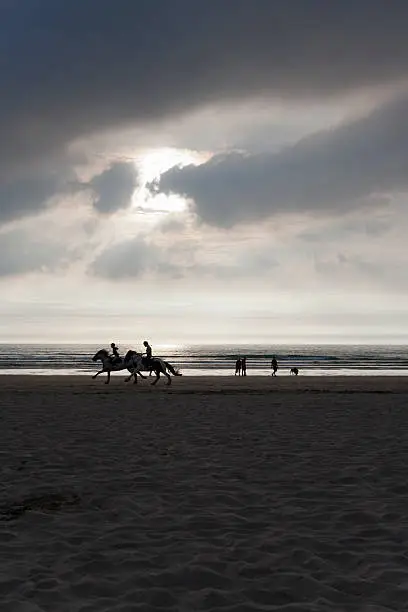 "Riders and walkers on the beach before sunset. Cornwall, UK."