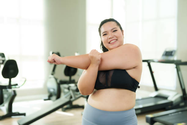 istock Beautiful overweight Asian woman does light exercise by stretching her arms and twisting her arms around after running and lifting dumbbells to relax during a time when she wants to lose weight. 1768719956
