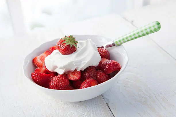 Strawberries with whipped cream in a small bowl