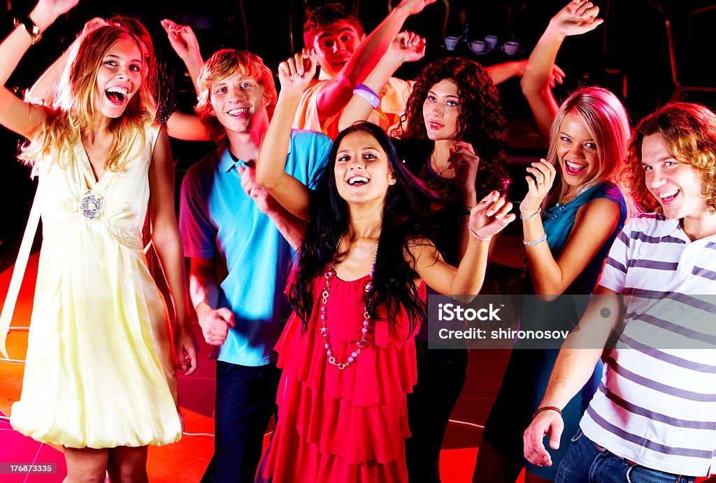 A group of friends in colorful attire dancing at a party Joyful teens dancing in night club at party Adolescence Stock Photo