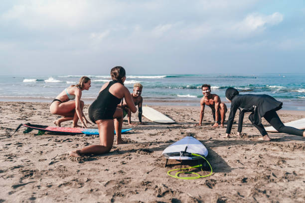 istock Male surfing instructor on board on beach giving lesson to group 1768735600
