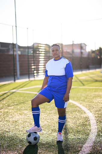 Full length portrait determined female soccer player looking at camera