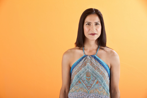 Confident young Latina woman on an orange background