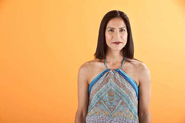 Confident Young Woman Confident young Latina woman on an orange background sleeveless top stock pictures, royalty-free photos & images