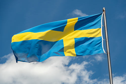 Mainau, Germany, July 20, 2023 Swedish flag is waving in the blue sky