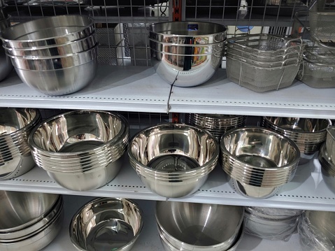 Metal kitchen utensils on shelves in supermarket.