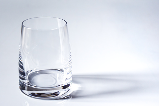 An abstract image or a background of an empty glass placed on top of a white table