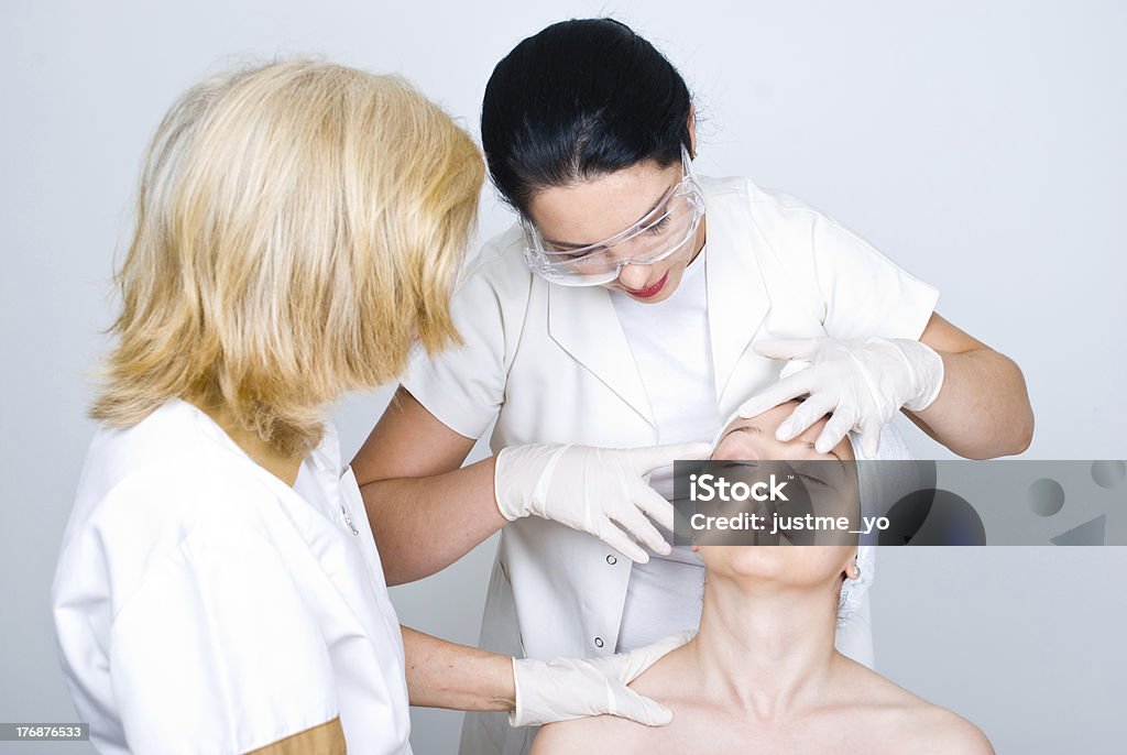 Doctor checking patient woman skin Two doctors women consulting a patient woman  skin and the young doctor pointing  and showing something  on patient face to her colleague  and preparing for botox treatment procedure Dermatology Stock Photo