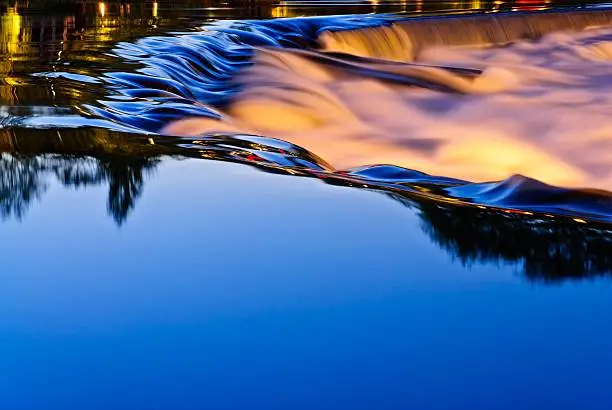 "Clean illuminated waterfall at dusk in Kongsberg, Norway with city lights in the background."