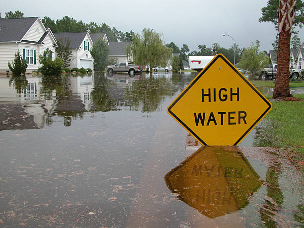 High Water Sign in Flooded Neighborhood Neighborhood flooded.  Sign warns of high water. flood stock pictures, royalty-free photos & images