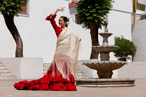 Traditional Woman Spanish Flamenco Dancer In Red Dress Woman traditional Spanish Flamenco dancer dancing in a red dress and cream shawl dancing in a town square with a stone fountain flamenco photos stock pictures, royalty-free photos & images