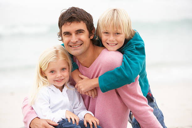 istock Father And Children Sitting On Winter Beach 176878571
