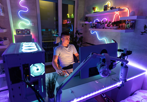 Teenager playing video games at night, in a room filled with led lights