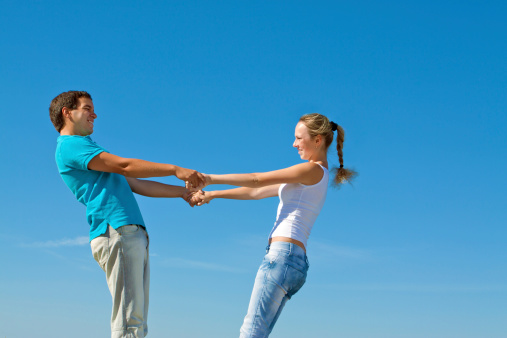 young couple holding hands against blue sky