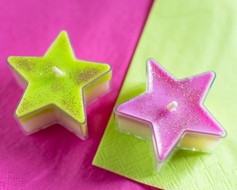 Tealight star candles in transparent cover, two-tone green-white and pink-white with glitter dust.