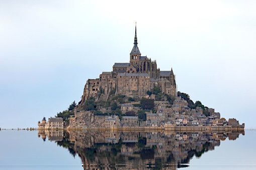 Reflected on the water at high tide of the Hill with the abbey of Mont Saint Michel in Normandy in Northern France