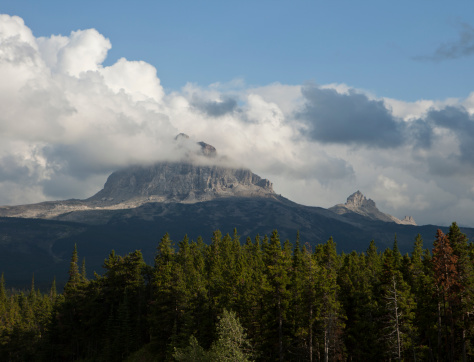 Big Chief Mountain in Glacier National Park on a day when it is surrounded by a halo of clouds. The mountain is a granite monolith that rises by itself in a corner of the park.