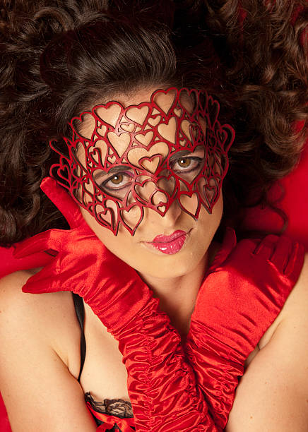 Young, beautiful Caucasian woman wearing red heart mask stock photo