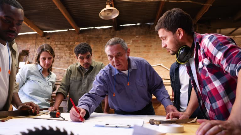 Diverse group of carpenters looking at a blueprint while discussing the project