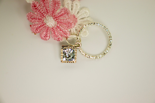 Close up of antique diamond ring with pink rose on pink background