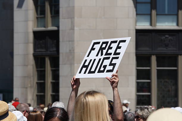 Free Hugs Sign Being Held Up "A man holding up a 'Free Hugs' sign on Canada Day in downtown Ottawa, Ontario, Canada." free hug stock pictures, royalty-free photos & images