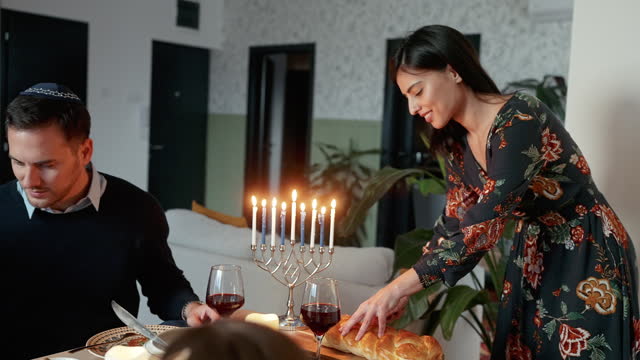 Close-up video of mother cutting Challah bread at the dining table