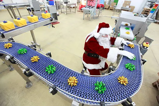 Photo of santa claus working at christmas ornament production line