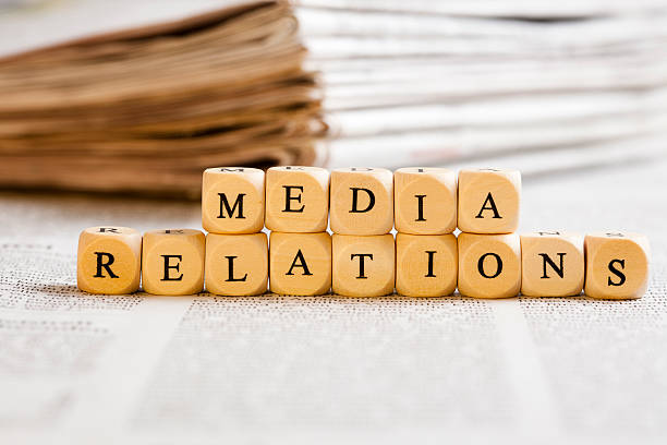 Letter Dices Concept: Media Relations Concept of dices with letters forming words: Media Relations. Generic newspaper background with some blurred text on the bottom and paper stack in the back. newspaper titles stock pictures, royalty-free photos & images