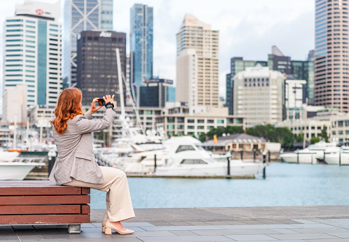 A woman taking a photo of downtown Auckland from