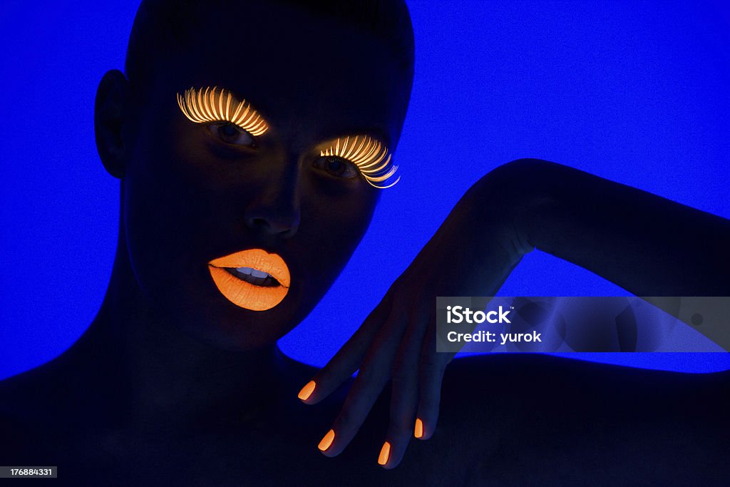 UV portrait close-up portrait of young woman wearing UV lashes and lipstick under blacklight Paint Stock Photo