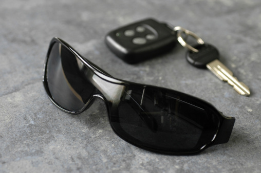 Black sunglasses and car keys sit on a slate countertop