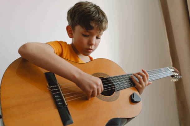 istock Cute boy learns to play the classical guitar 1768857974