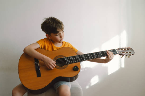 istock Cute boy learns to play the classical guitar 1768858012