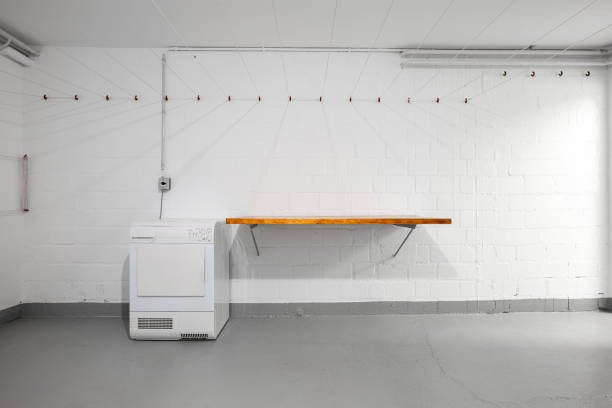 istock Apartment building common use empty laundry room. Empty wooden table top, dryer and hanging wires on the wall. Wide-angle view, no people 1768863018