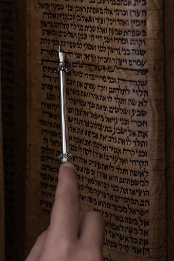 A reader uses a pointer to guide his eyes across the text of a Sephardic Torah scroll during a Jewish prayer service.