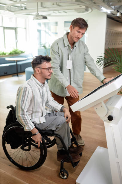 istock Man helping to make online entry for man with disability 1768881187