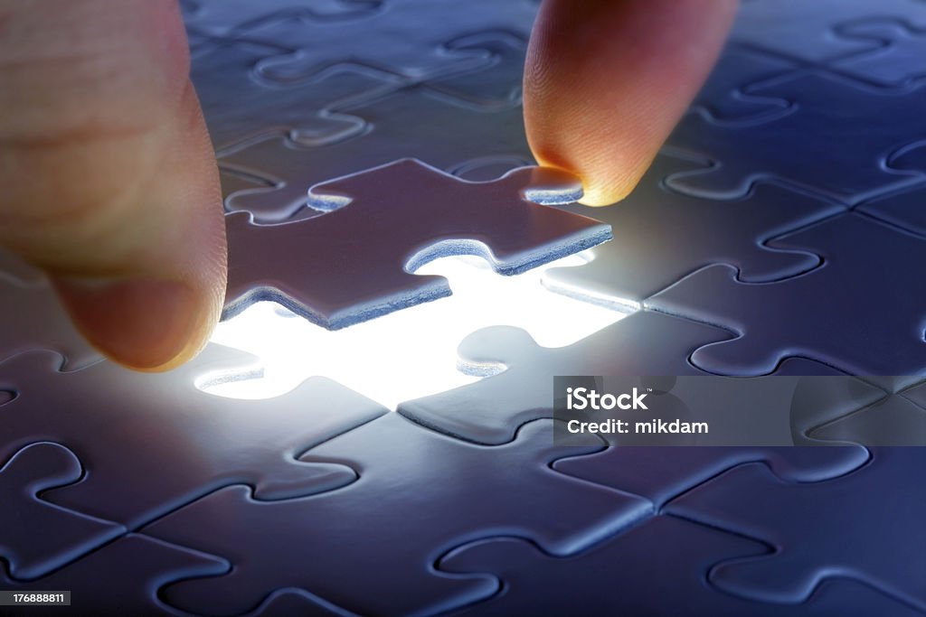 One puzzle piece over empty glowing spot in puzzle puzzle piece coming down into it's place Business Stock Photo