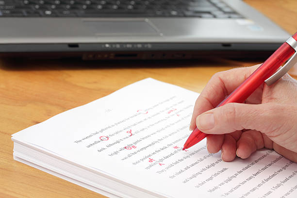 Close-up of a hand proofreading a manuscript with a red pen stock photo