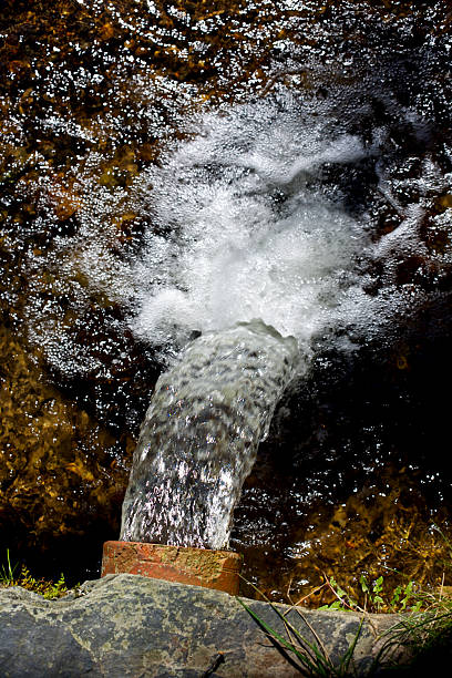 Clear mountain spring water flows from a 6 inch pipe stock photo