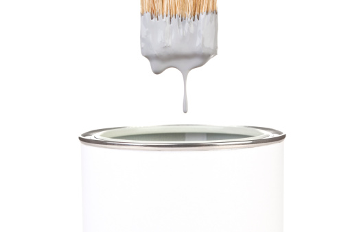 Grey paint dropping from brush into can isolated on white background. DIY creativity concept.