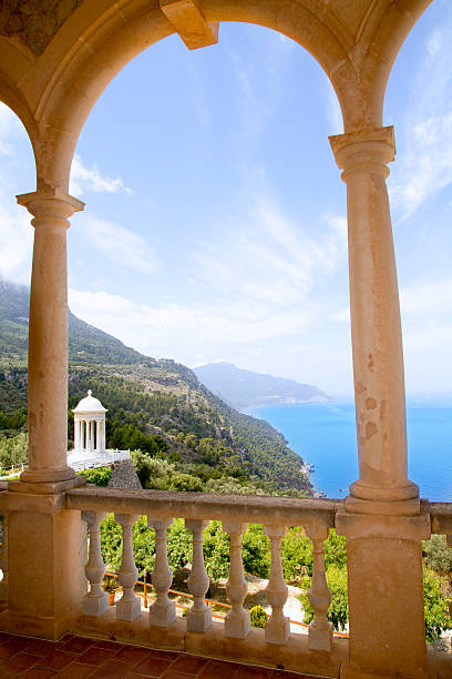Seascape view from a charming balcony, with open doors and white chairs and in the foreground.