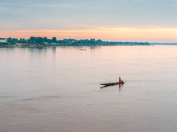 Middle-aged man driving a boat A middle-aged man drives a boat to make a living following a simple lifestyle on the Mekong River. Nong Khai Province, Thailand nong khai stock pictures, royalty-free photos & images