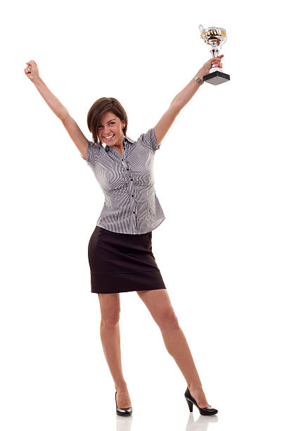 Studio shot of a young businesswoman standing with his fists raised in celebration against a gray background