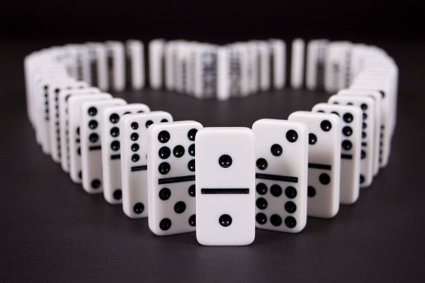 Dominos on black background in the shape of a heart.  Leading domino has two single dots symbolic of two in love.
