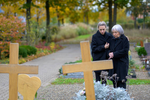 前景の墓地の母と娘、2つの木製の十字架 - grief women selective focus outdoors ストックフォトと画像