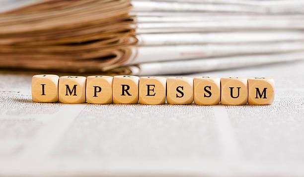 Letter Dices Concept: Impressum (German) Concept of dices with letters forming word: Impressum (German for Imprint). Generic newspaper background with some blurred text on the bottom and paper stack in the back. newspaper titles stock pictures, royalty-free photos & images